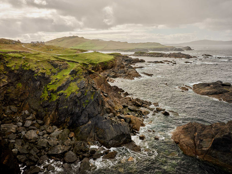 Coastal landscape with rocky cliffs and ocean waves on a cloudy day.
